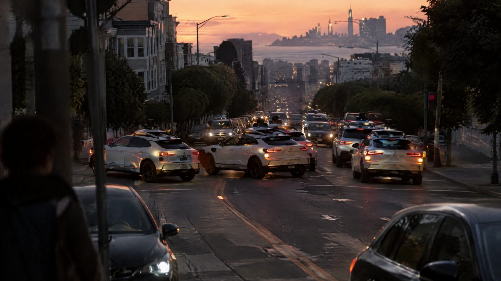 Several white self-driving cars stalled at angles across a dark city street